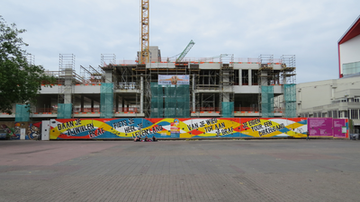 828669 Gezicht op de nieuwbouw aan de westzijde van het plein Vredenburg te Utrecht, met op de bouwschutting ...